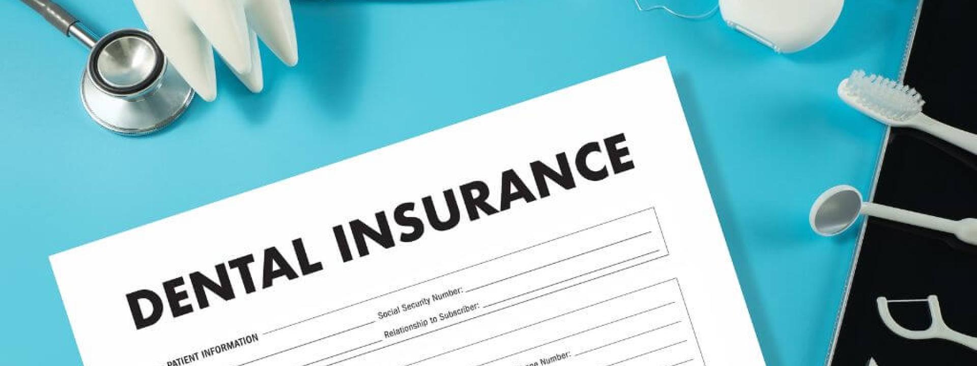 Dental insurance form on a clipboard surrounded by dental tools